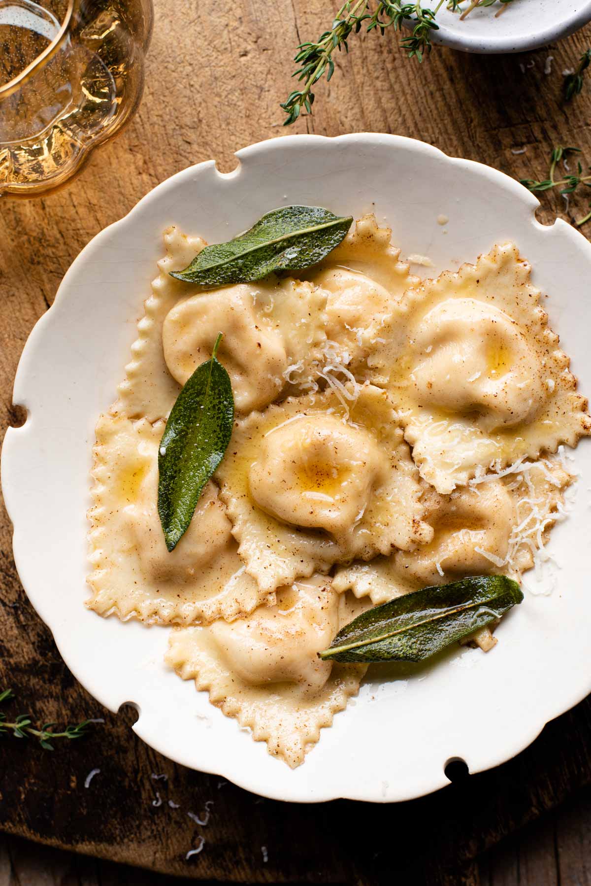 An overhead shot of butternut squash ravioli in a white bowl sitting on a wooden serving board.