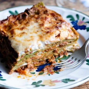A close up of a slice of Lasagna Bolognese on a plate with a flower pattern.