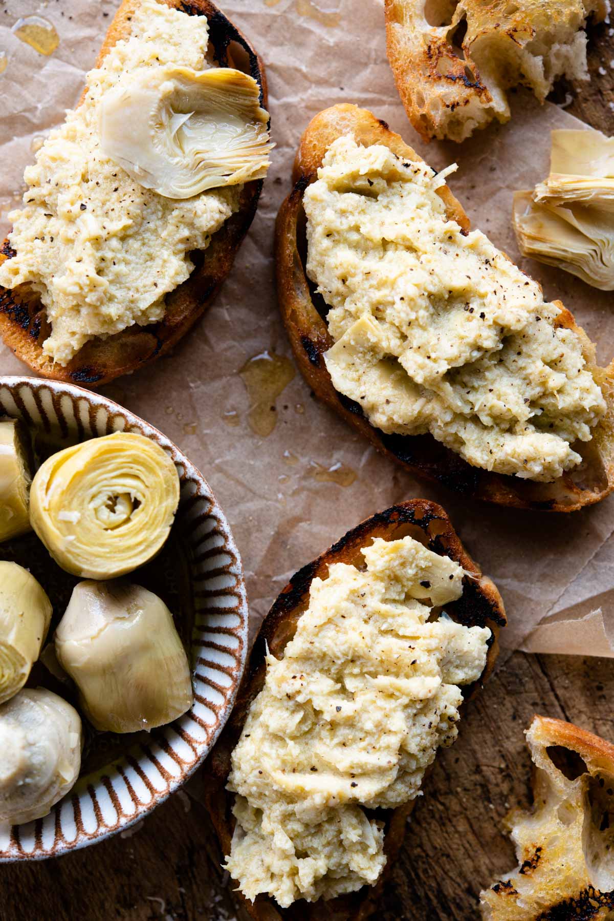 A close up of three pieces of artichoke bruschetta sitting on baking parchment.