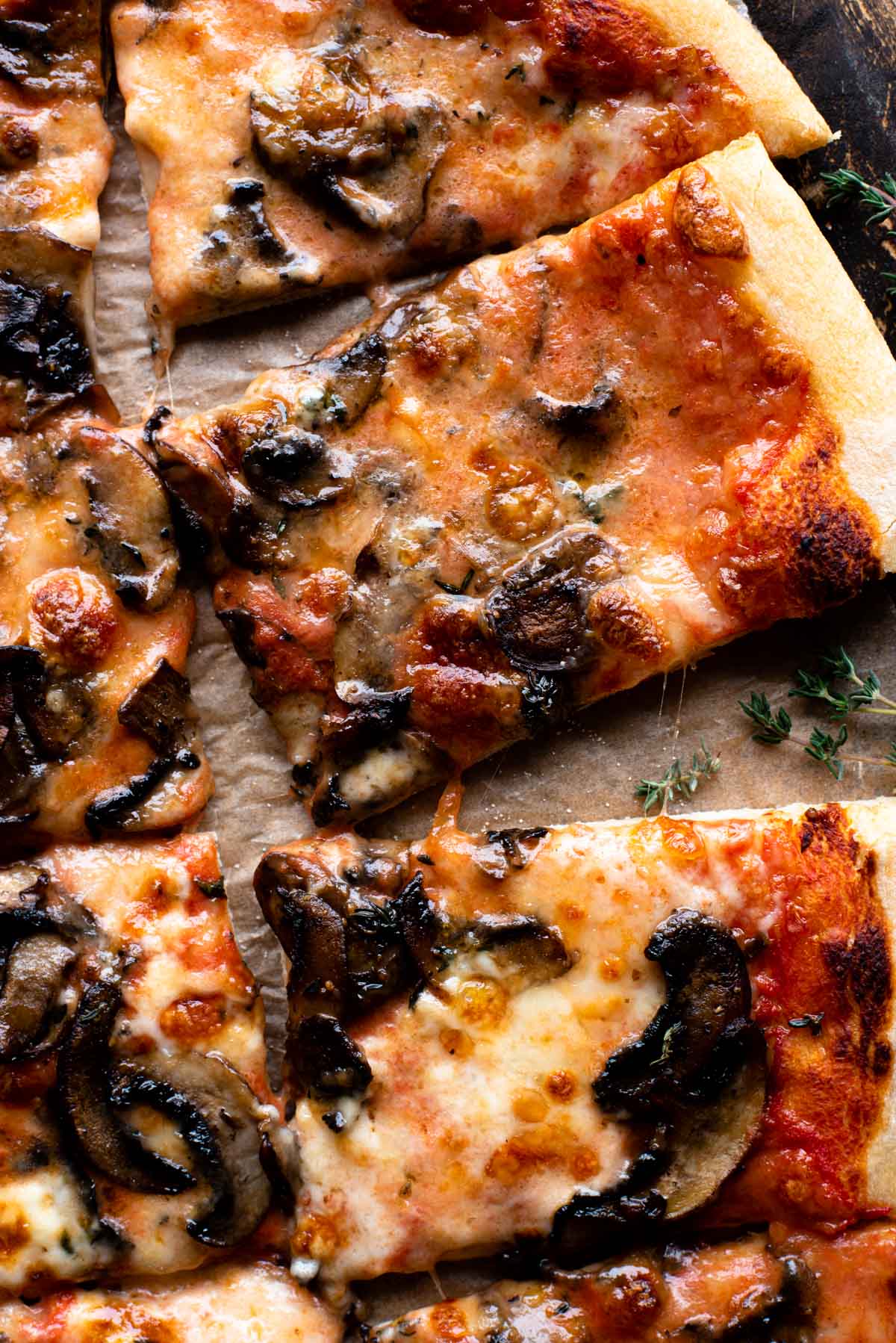 A close up of a mushroom pizza with taleggio cheese on a wooden surface.