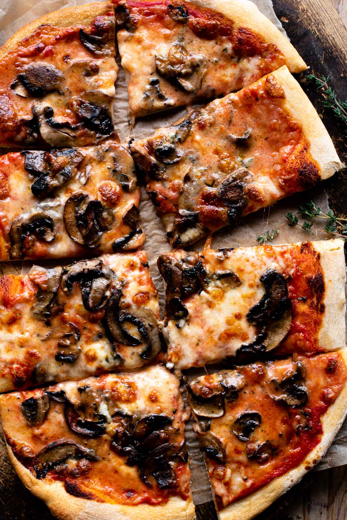 Fotografía cenital de una pizza de champiñones y taleggio cortada en 8 porciones.
