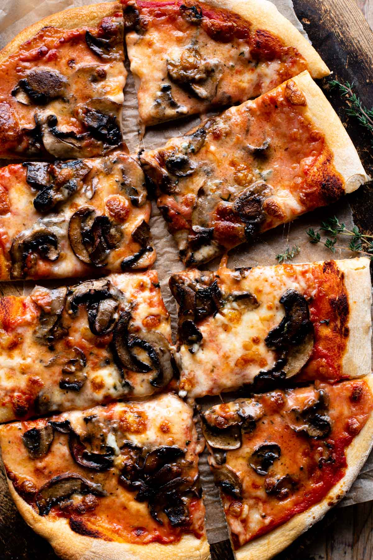 A mushroom pizza on a wooden surface cut into slices.