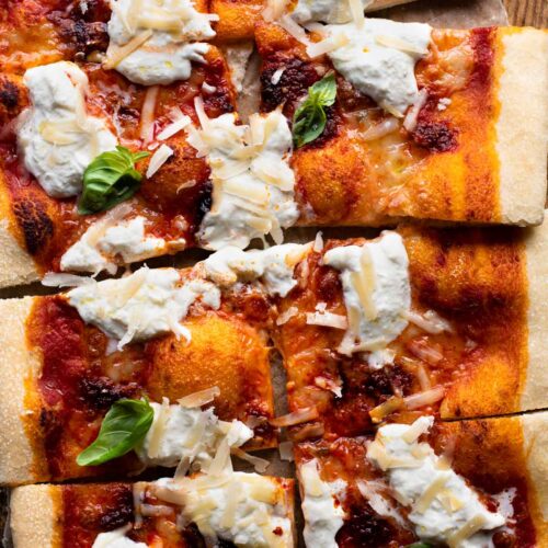 An overhead shot of a large Nduja pizza with burrata cheese and basil cut into 8 slices.