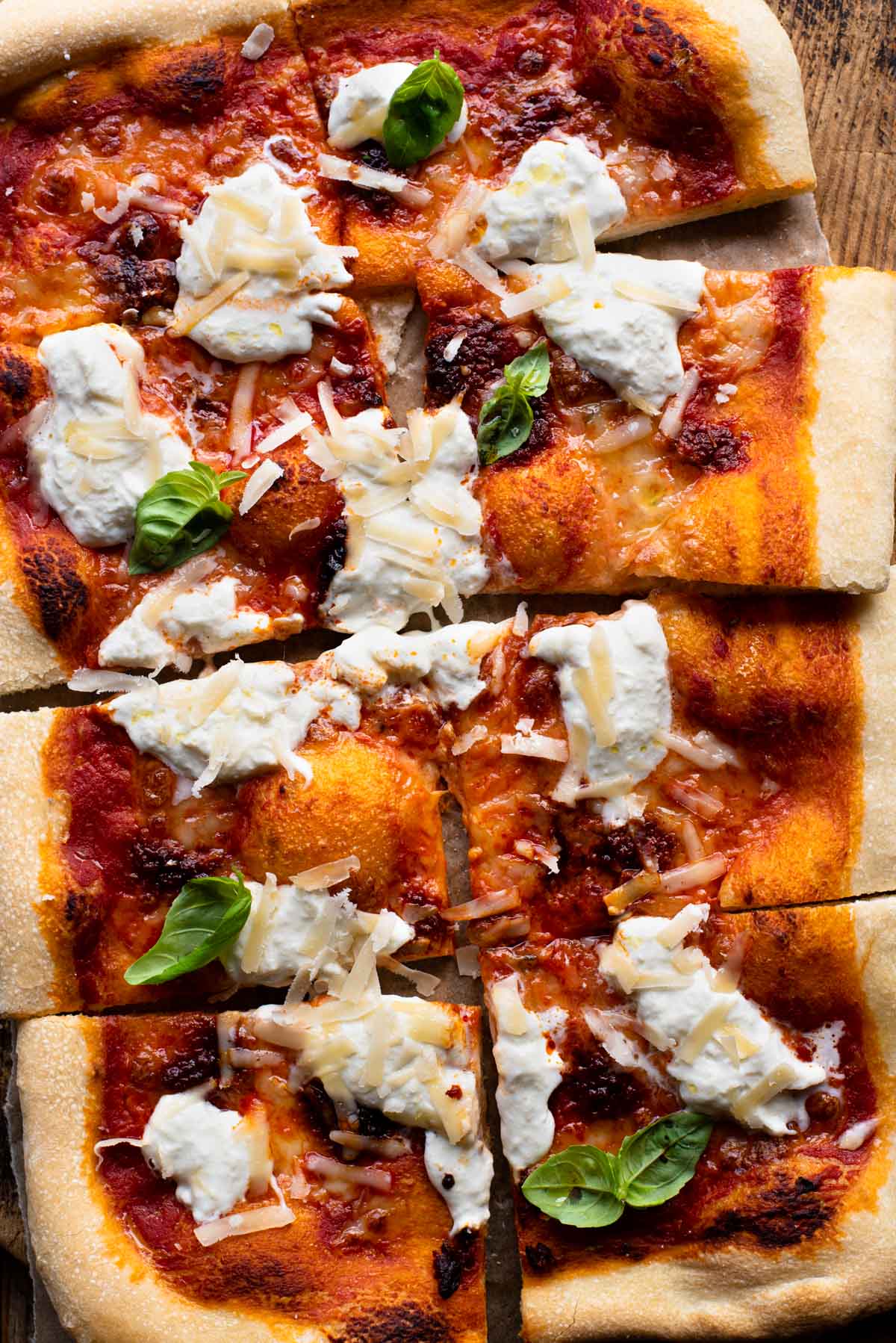 An overhead shot of a large Nduja pizza with burrata cheese and basil cut into 8 slices.