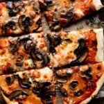 A close up cropped image of a mushroom pizza cut into slices.