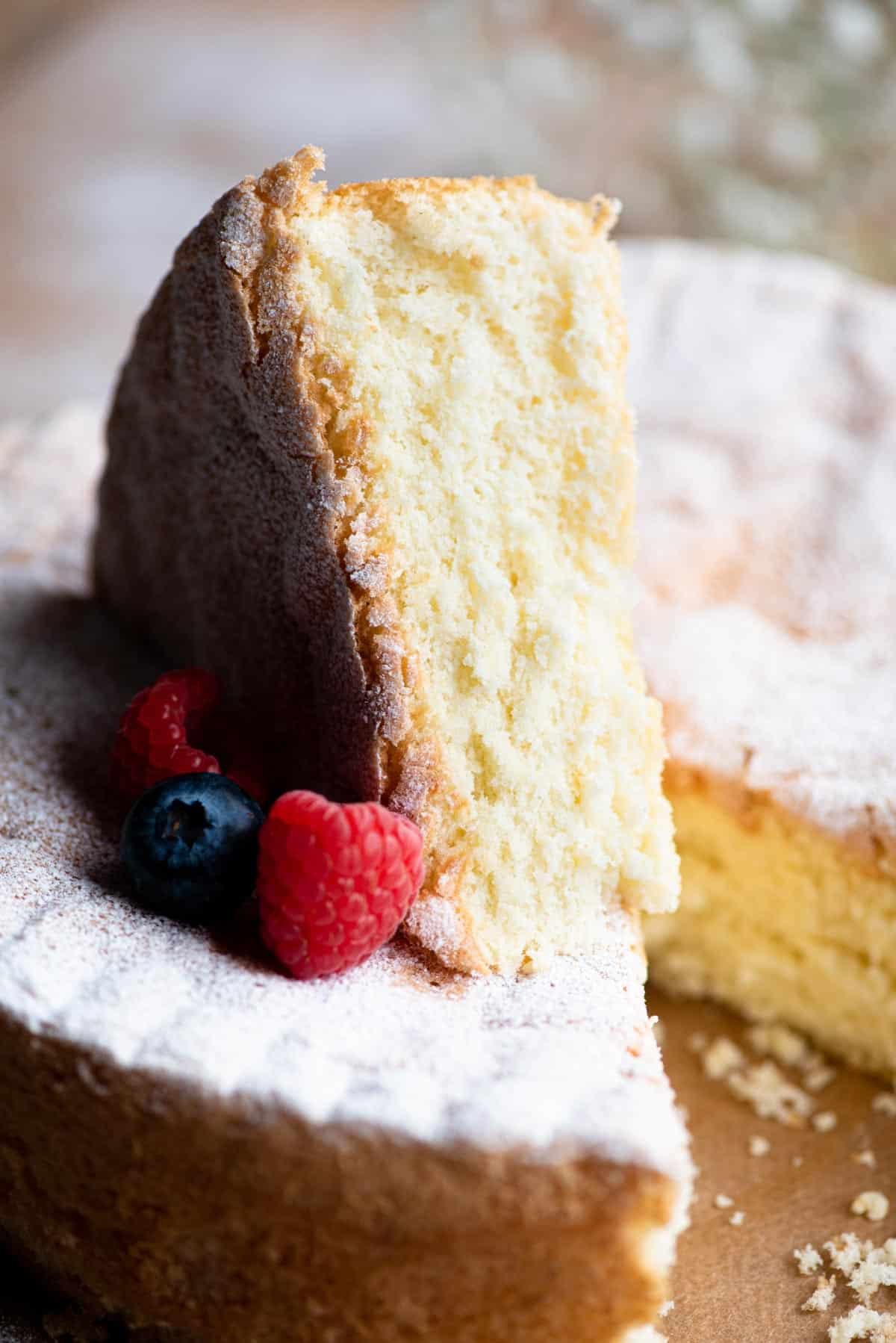 Close up of a slice of Italian Pan di Spagna sponge cake with berries at the side.