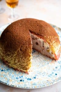A dome shaped Italian dessert called Zuccotto on a patterned plate with a slice cut out.