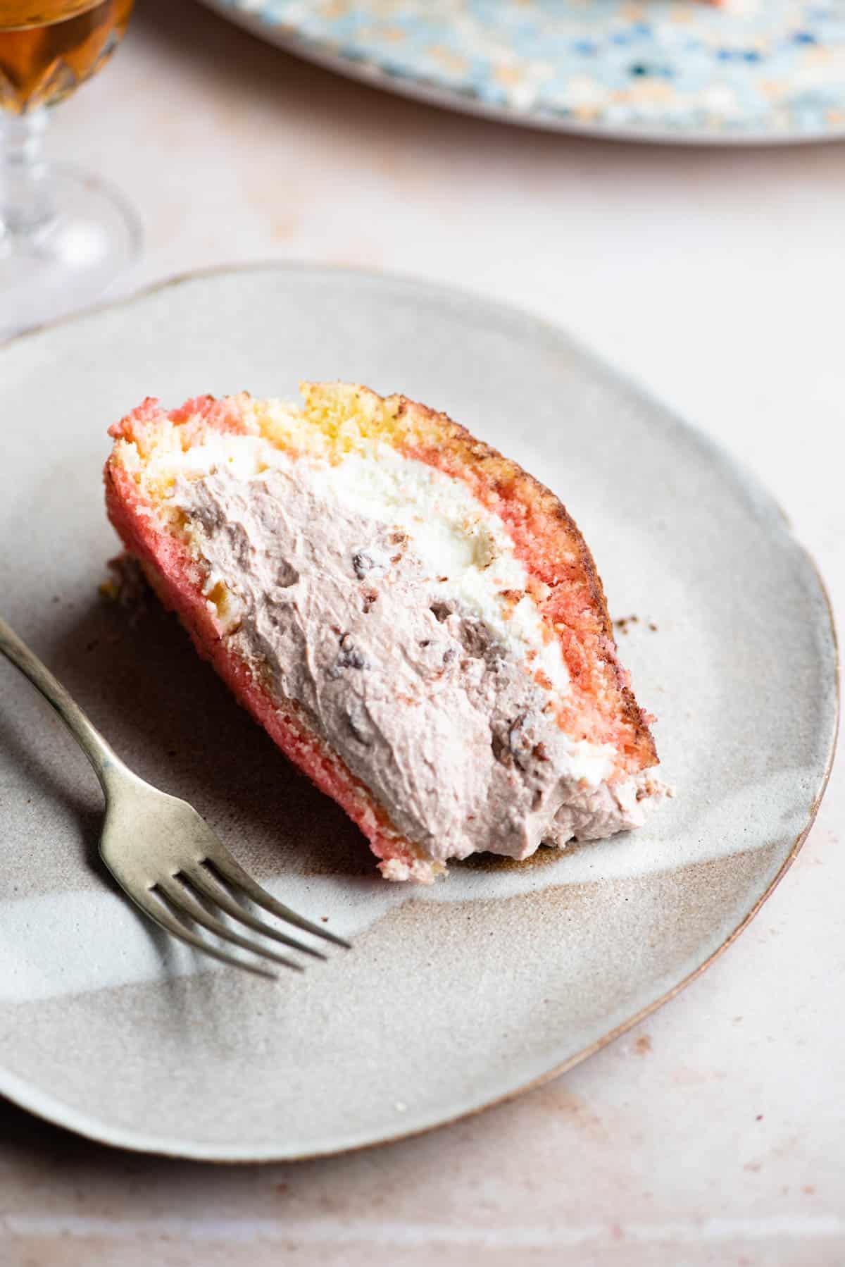 A slice of Italian Zuccotto cake on a plate with a fork at the side.