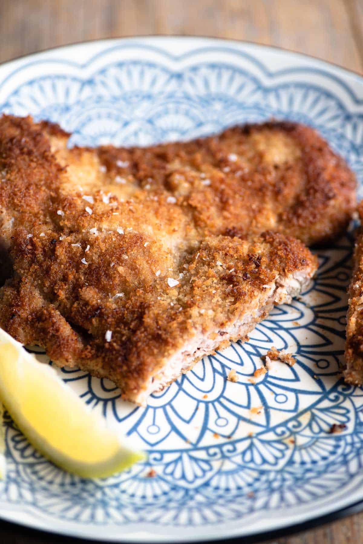 A close up of Veal Milanese on a plate with a slice cut.