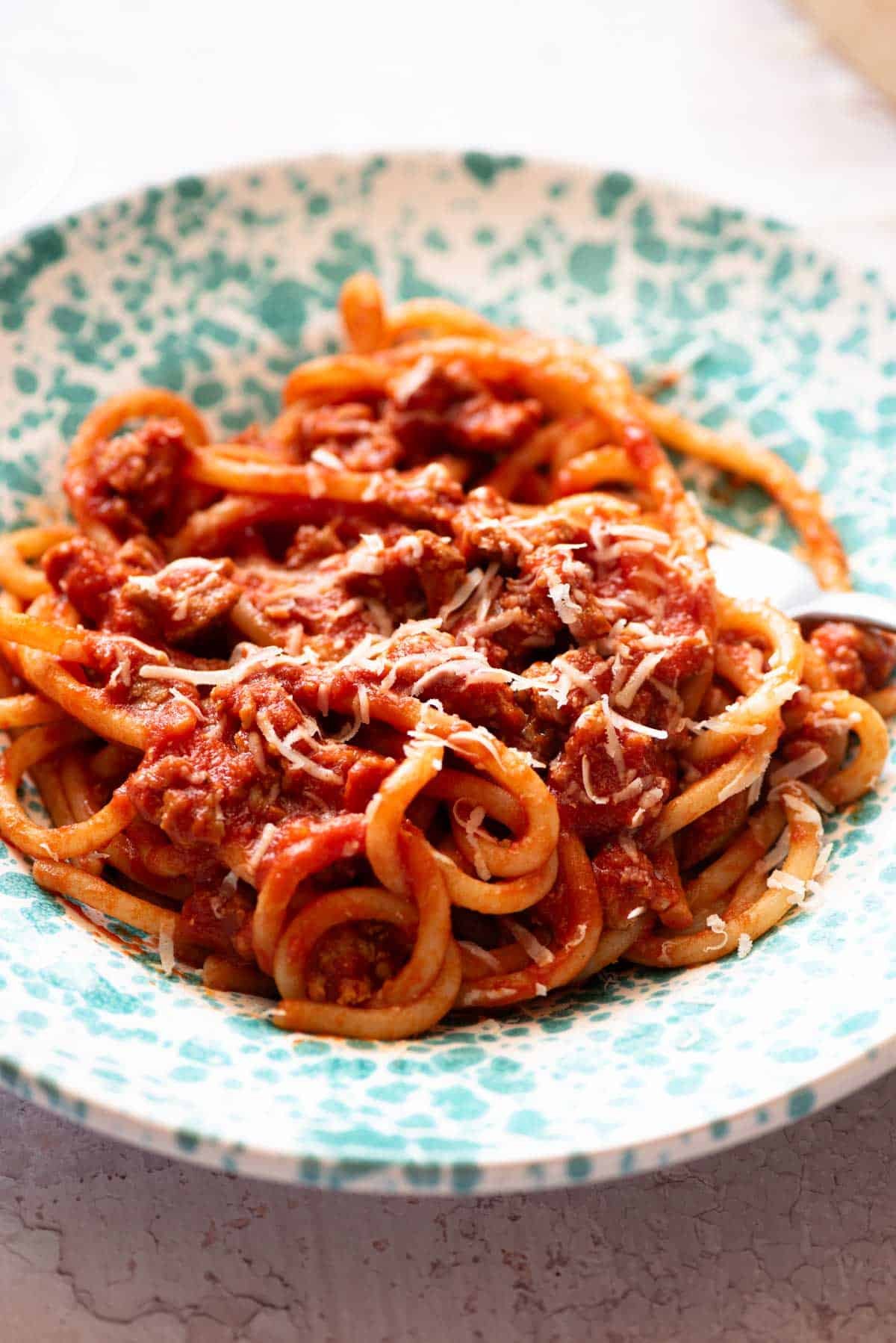 A close up of Tuscan sausage pasta in a blue bowl.