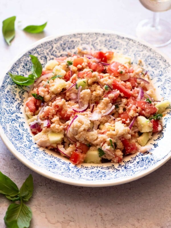 Authentic Tuscan Panzanella Salad in a blue patterned bowl with basil around.