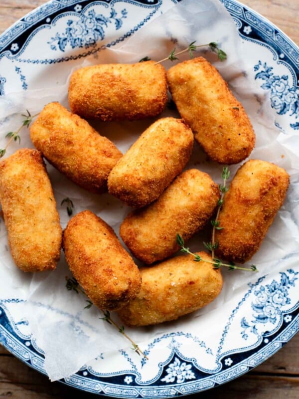 An overhead shot of chicken croquettes in a blue bowl with sprigs of thyme.