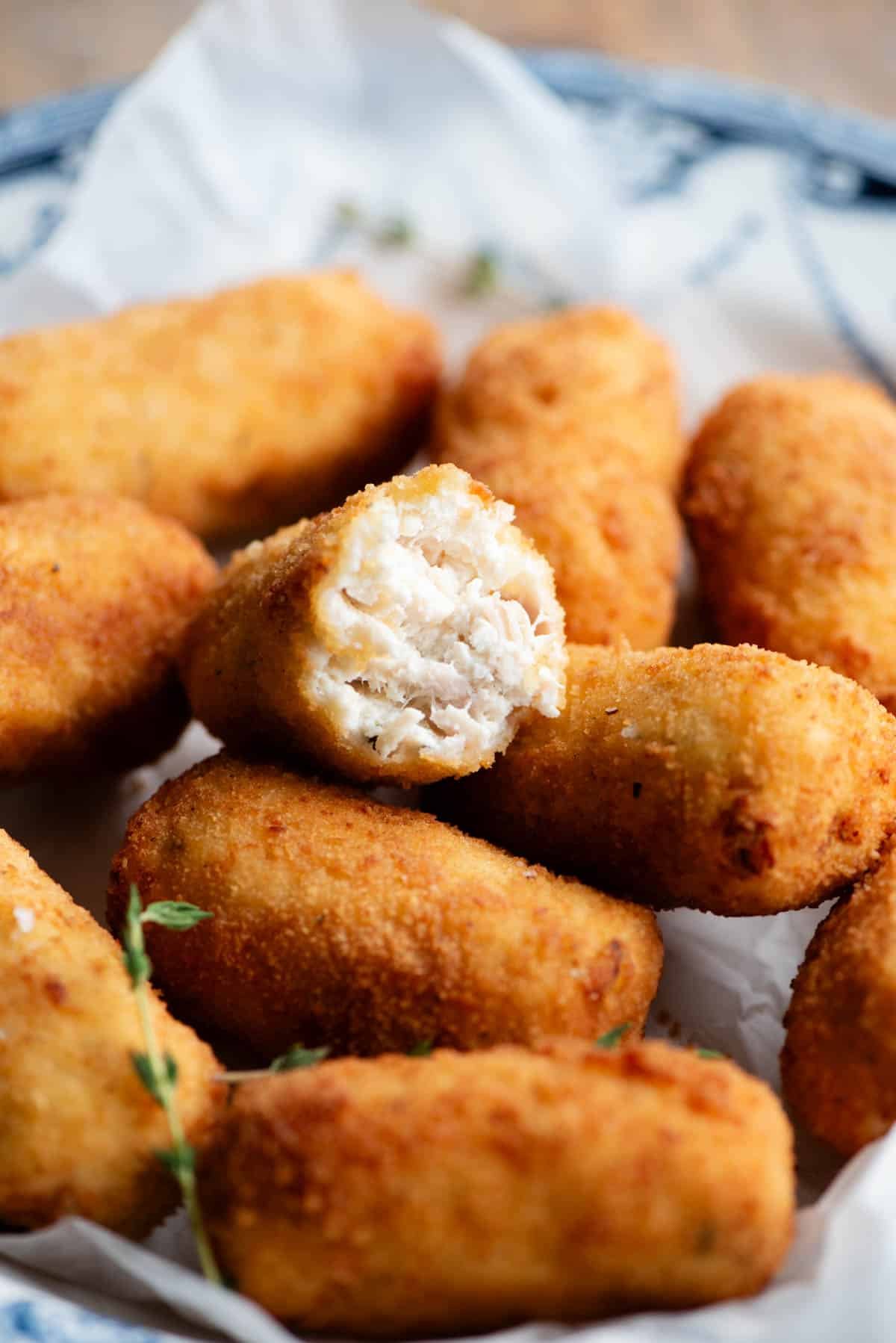 A close up of half a chicken croquette piled on top of others in a bowl.