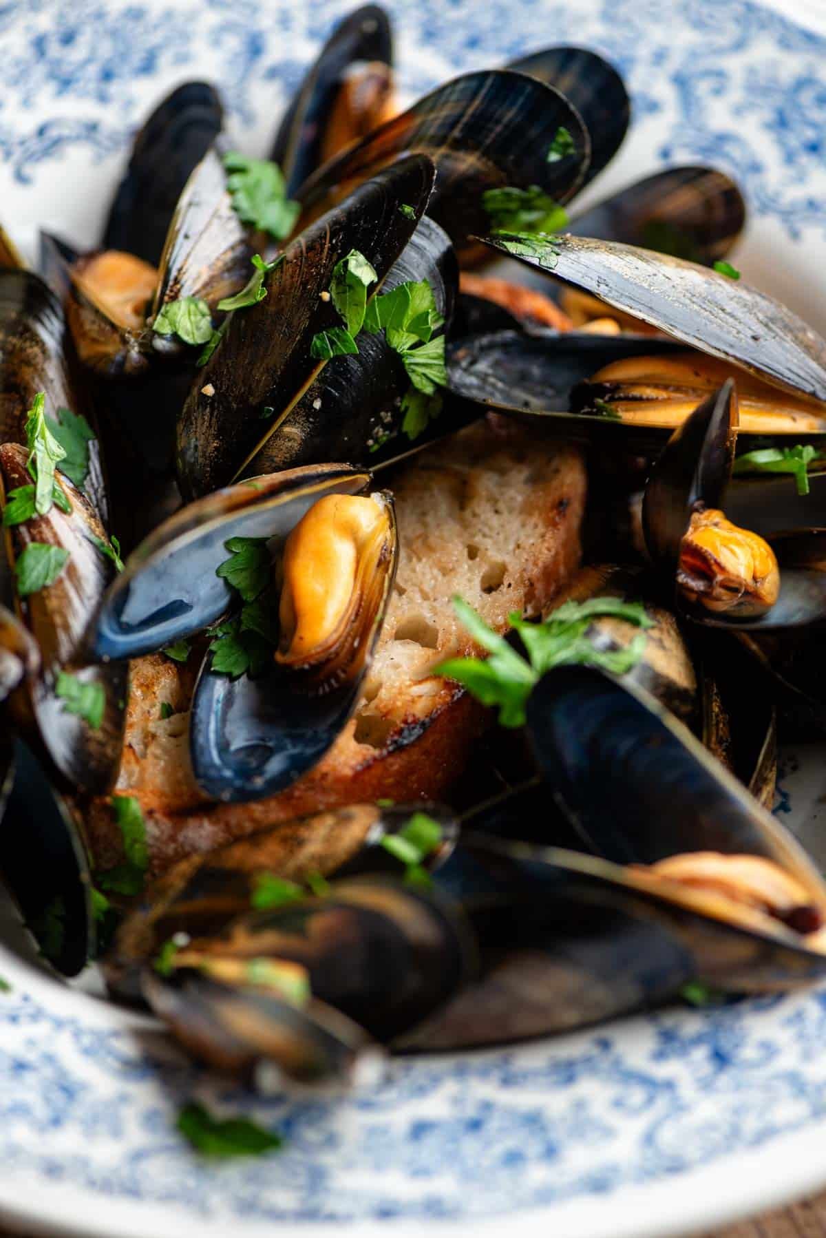 A close up of peppered mussels on top of a piece of ciabatta bread.