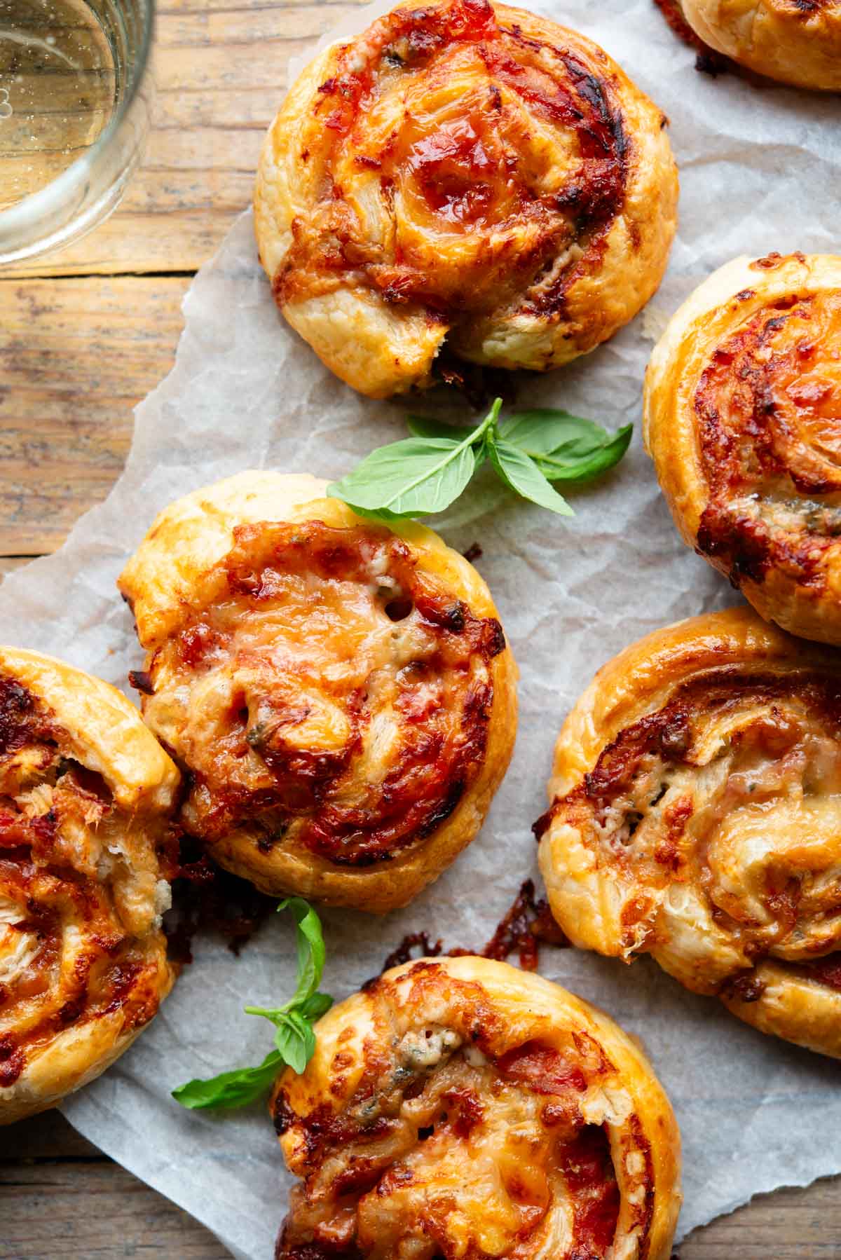 An overhead shot of pizza pinwheels on a sheet of baking parchment.