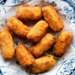 A close up cropped image of chicken croquettes in a blue and white bowl.