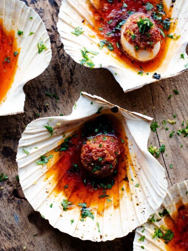An overhead shot of scallops in their shells with a Nduja garlic butter on top.