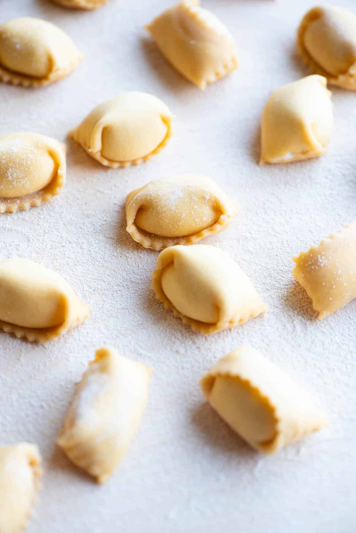 A close up side shot of homemade Agnolotti on a wooden board.