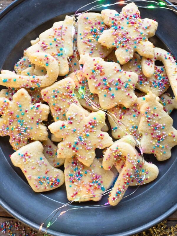 An overhead shot of Befanini Tuscan Christmas cookies cut into Christmas shapes on a plate topped with spinkles.