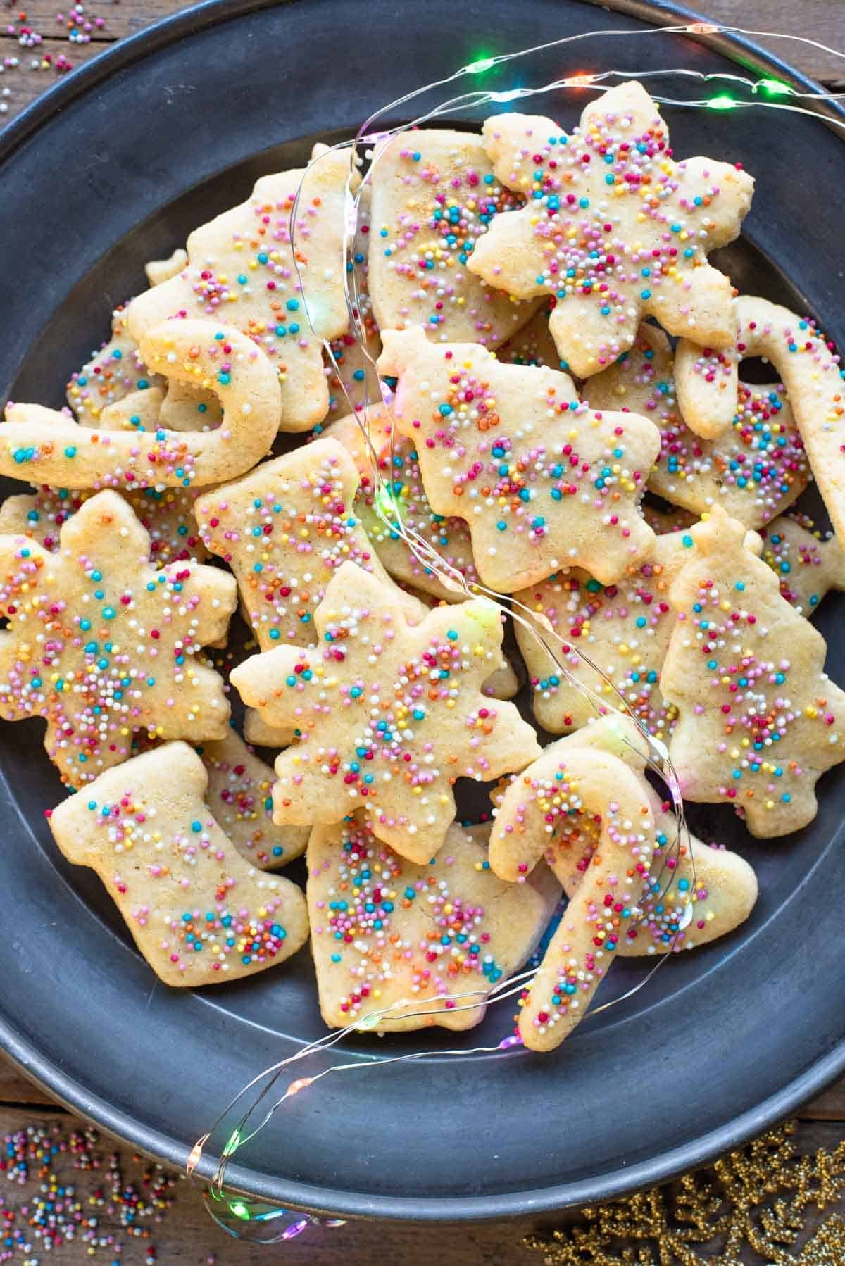 An overhead shot of Befanini Tuscan Christmas cookies cut into Christmas shapes on a plate topped with spinkles.