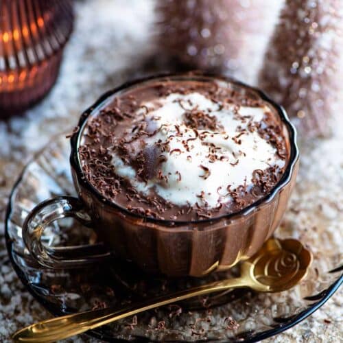 Hot chocolate in a glass mug with ice cream on top and fake snow around.