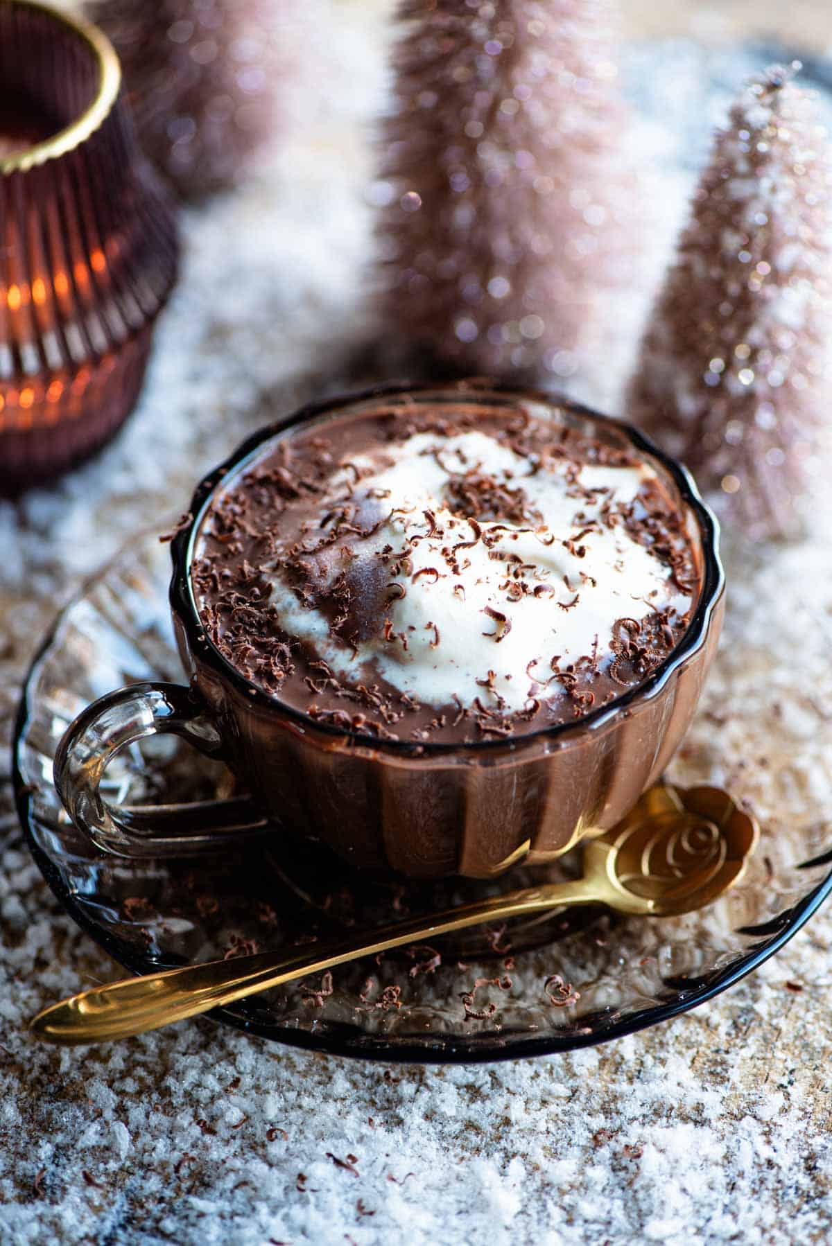 A class mug of hot chocolate with ice cream on top and snow all around.