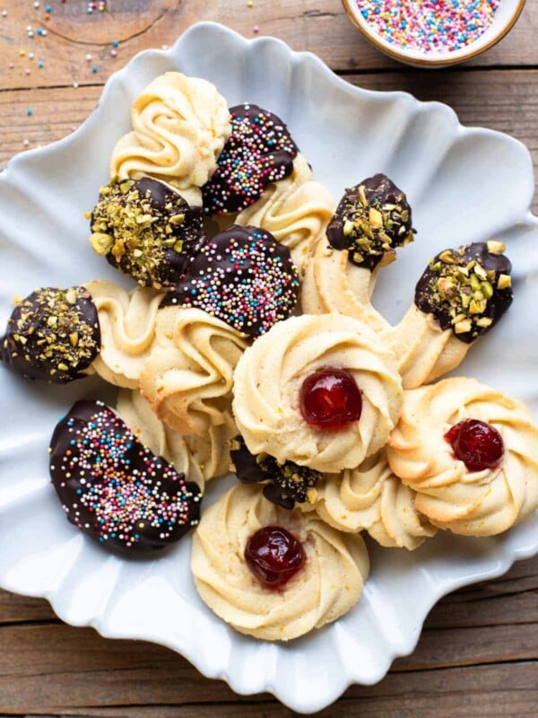 An overhead shot of Italian butter cookies on a star shaped plate covered with chopped nuts and sprinkles. The background is wooden.