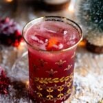 A close up of a Christmas Cocktail made of Cranberry juice and Prosecco in a gold glass.