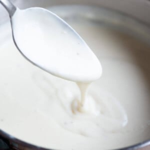 A close up of a Italian Bechamel Sauce (Besciamella) on a spoon in a pot.
