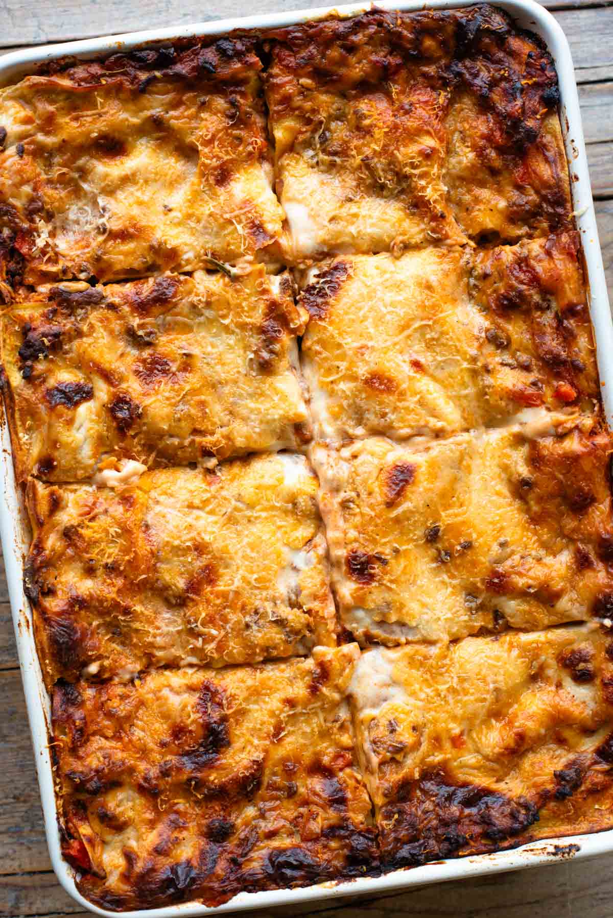 An overhead shot of a lamb lasagna in a large baking dish cut into 8 pieces.