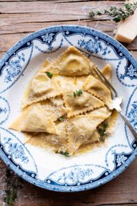 An overhead shot of taleggio and mushroom Triangoli pasta in a blue bowl with a butter sauce.