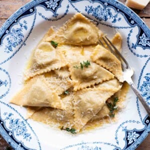 An overhead shot of taleggio and mushroom Triangoli pasta in a blue bowl with a butter sauce.