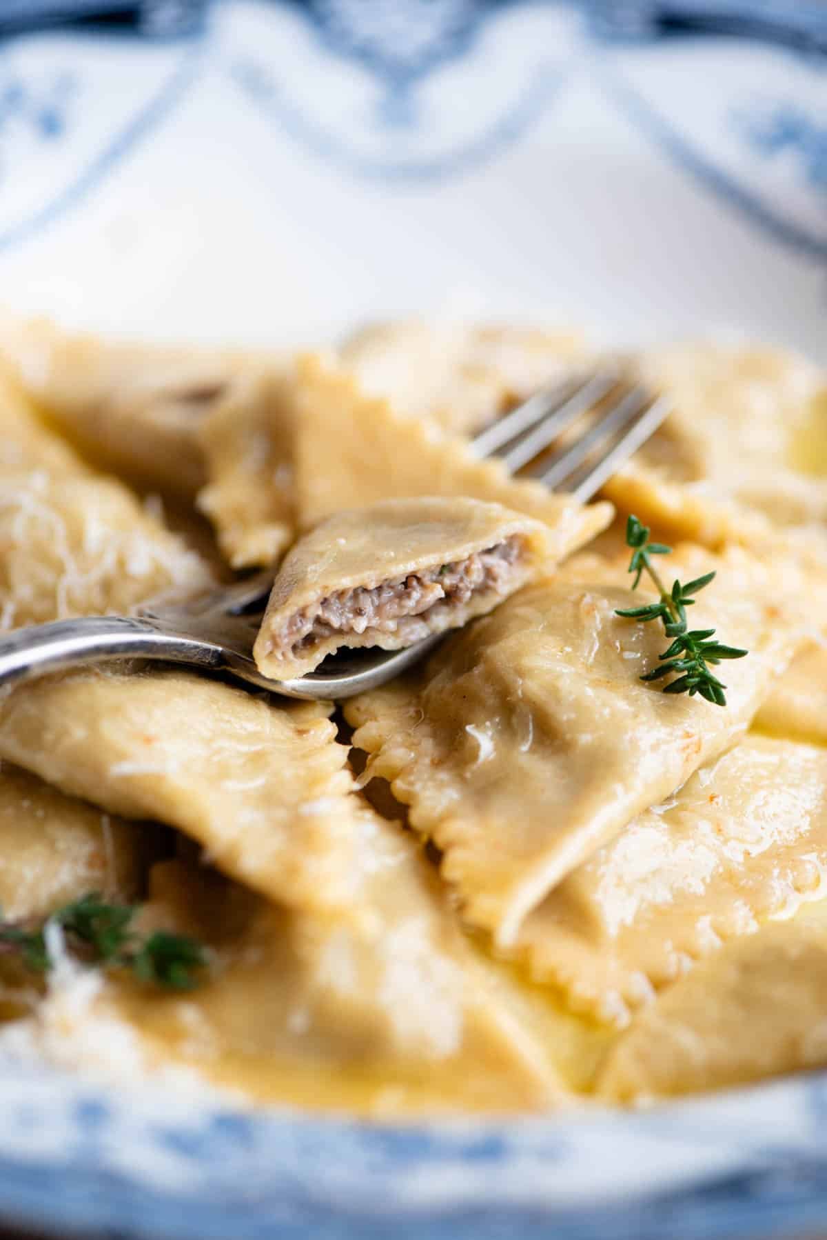 A close up side shot of mushroom and taleggio Triangoli pasta with one cut open to see the filling inside.