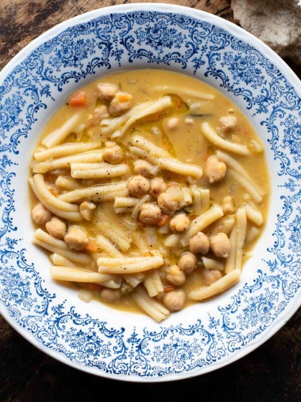 An overhead shot of pasta e ceci (psta and chickpeas) in a blue bowl on a wooden surface.