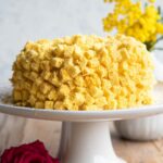 A close up cropped image of a mimosa cake on a cake stand.