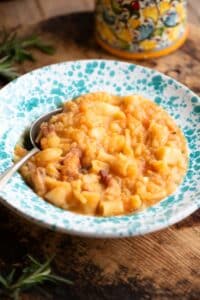 Pasta e Patate (potatoes) in a blue speckled bowl with a spoon sitting on a wooden surface.