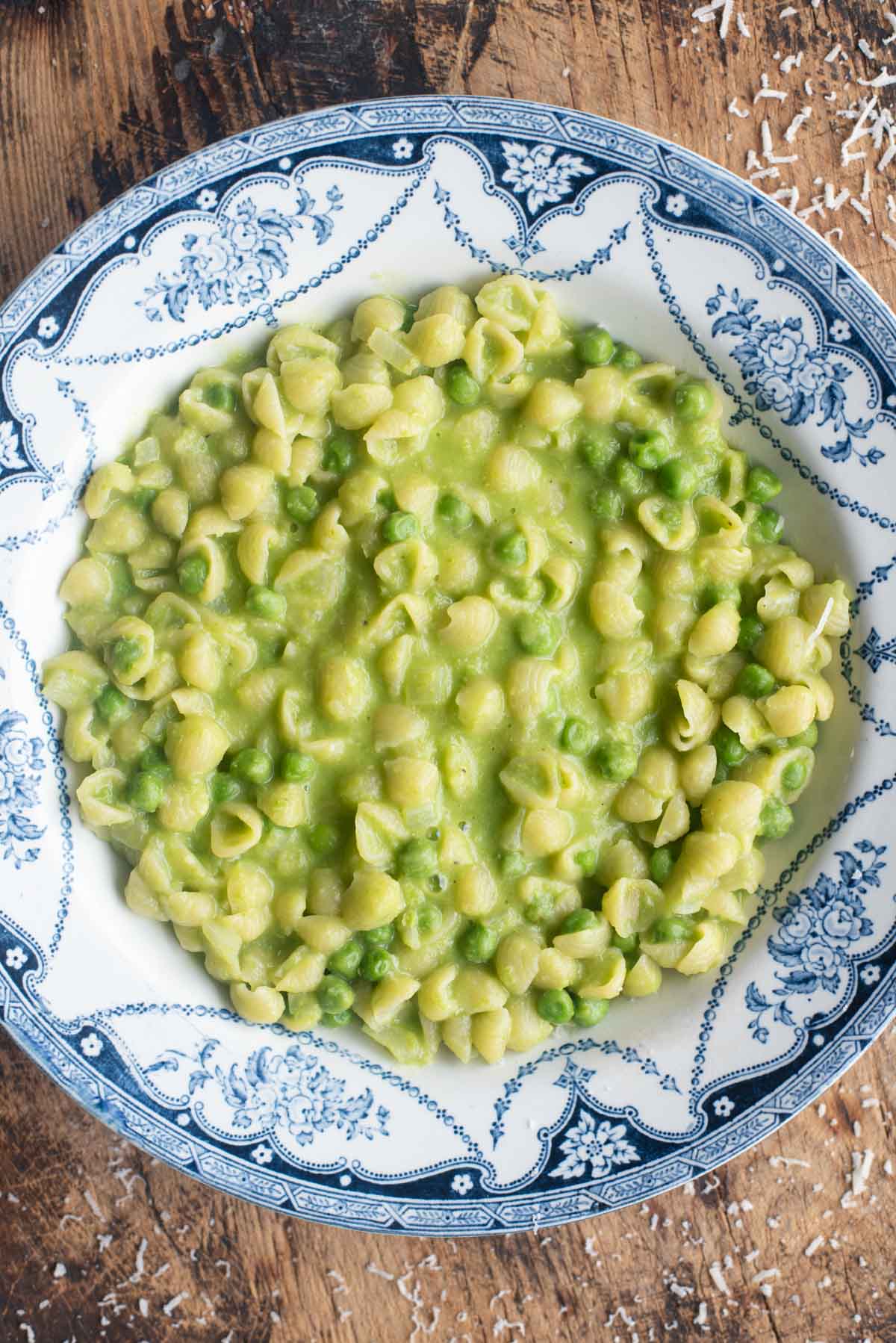 A close up of pasta and peas in a blue and white bowl.