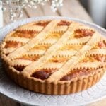 A cropped square image of a Pastiera Napoletana (Italian Easter dessert) on a cake stand.