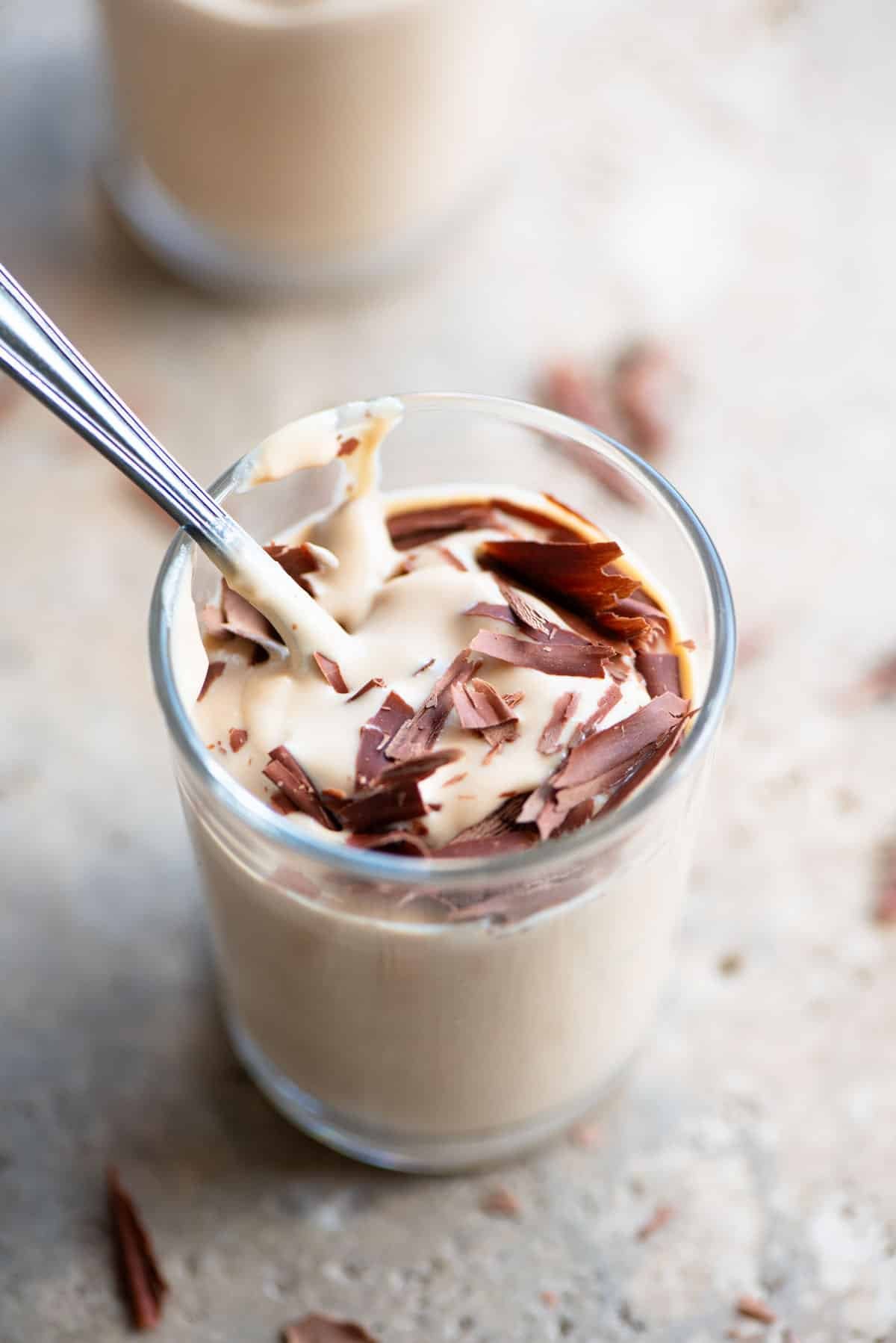 A close up of ricotta and coffee in a small glass with a spoon inside.