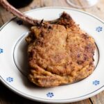 A cropped image of an Italian breaded veal chop on a plate.