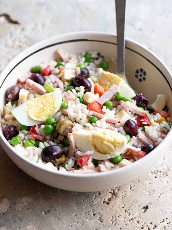 A traditional Italian rice salad in a bowl sitting on a rustic stone work top.