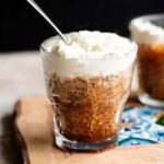 A cropped square image of a small glass filled with coffee granita and topped with whipped cream.