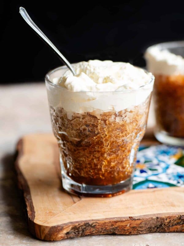 A small glass of coffee granita topped with whipped cream and a spoon in it.