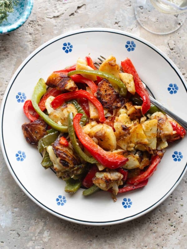 An overhead shot of peppers and potatoes on a plate with a fork at the side.