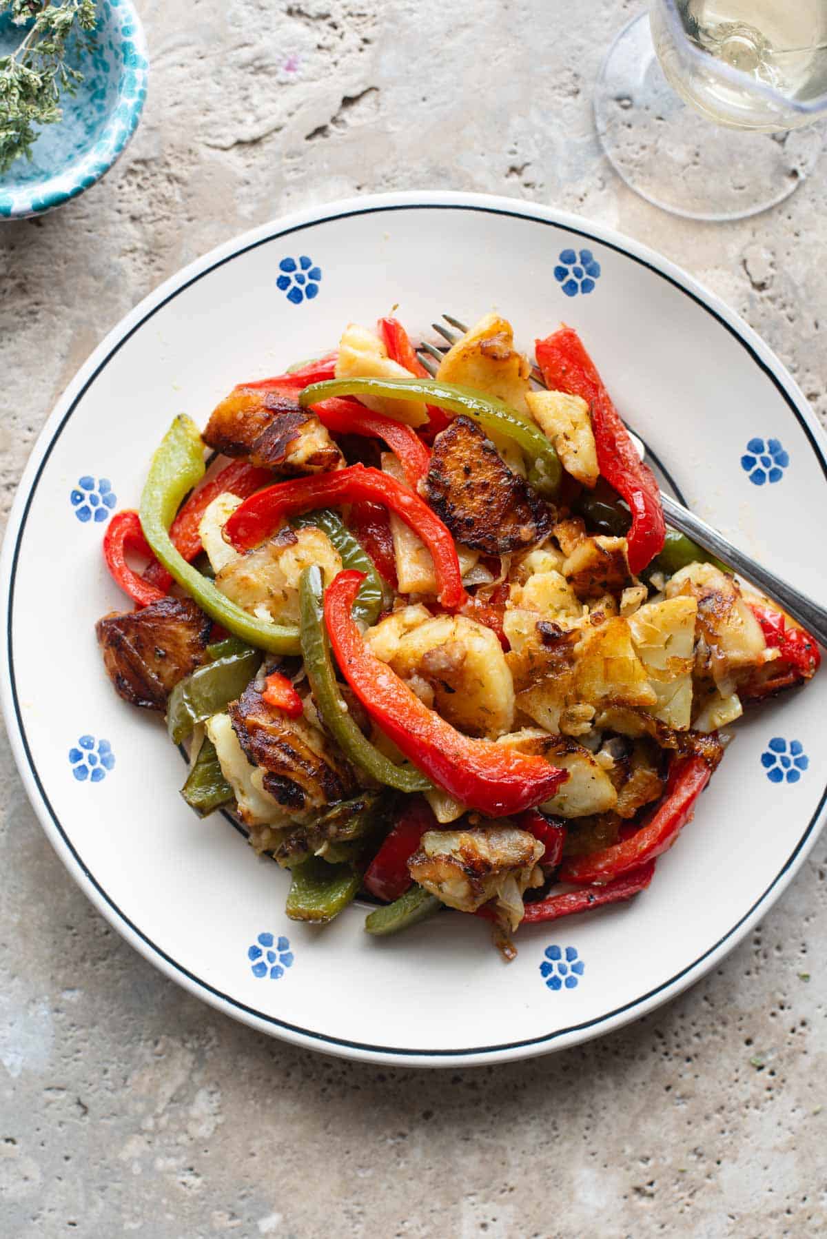 An overhead shot of peppers and potatoes on a plate with a fork at the side.