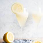 A close up of an Italian Sgroppino cocktail in a flute glass with a slice of lemon on the side.