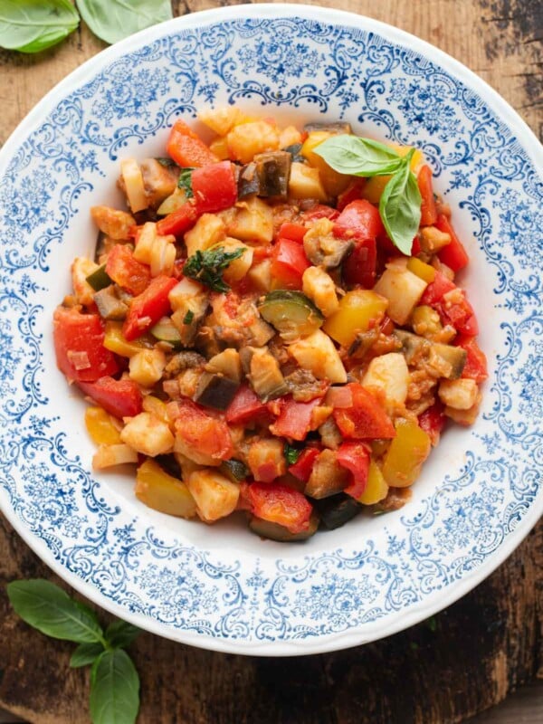 An overhead shot of Ciambotta (Italian vegetable stew) in a blue bowl, the background is wooden.