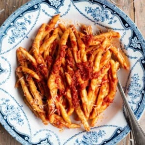 An overhead shot of a spicy tomato Nduja pasta in a blue and white bowl.
