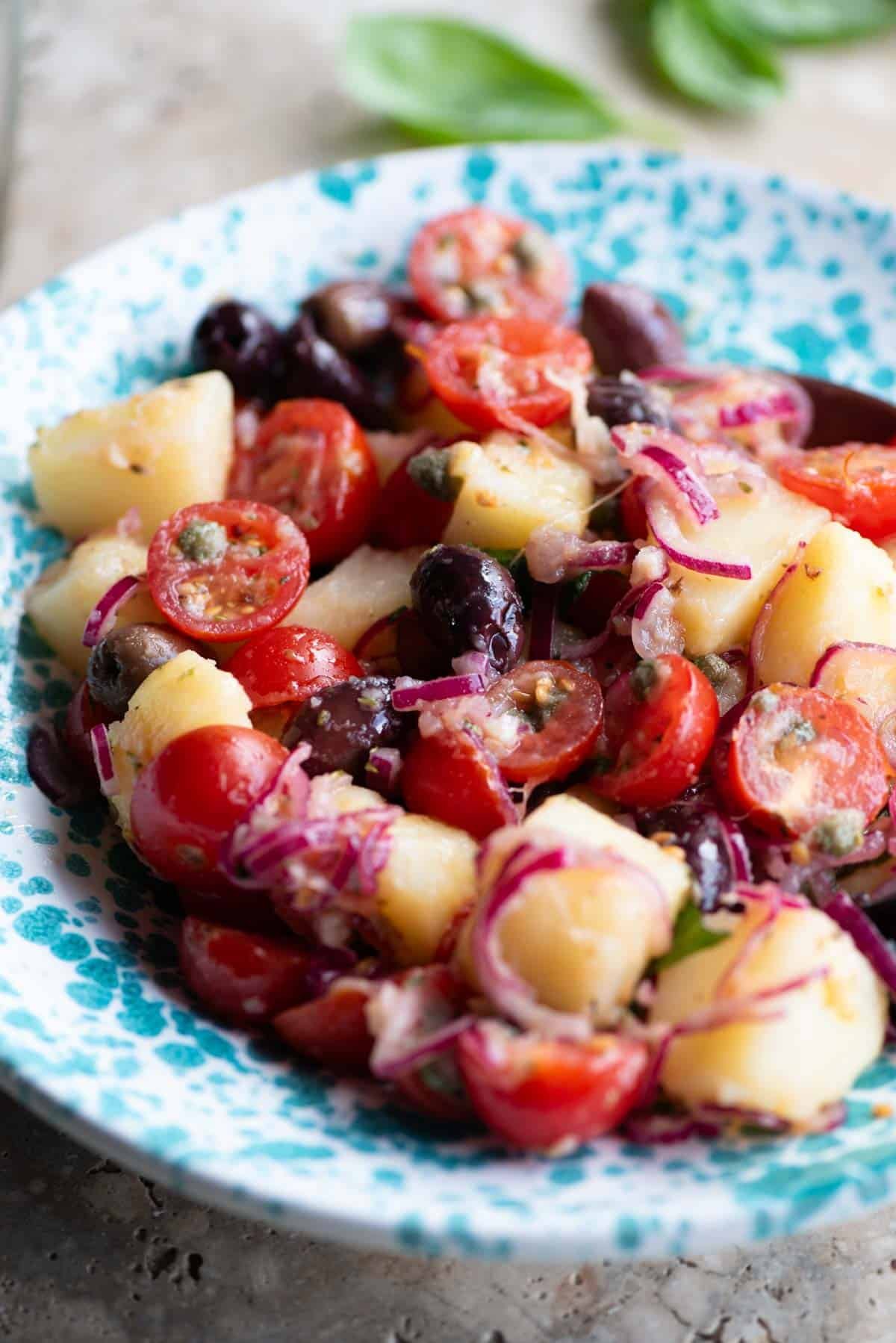 A close up of a Sicilian potato salad in a blue and white bowl.