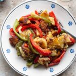 A cropped overhead shot of potatoes and peppers on a traditional Italian painted terracotta plate.